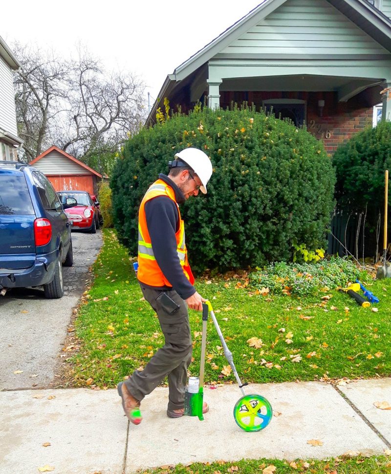 Informative Image of multiVIEW Utility Locating Technician marketing sidewalk with paint to identify buried utilities in front of homeowner property.